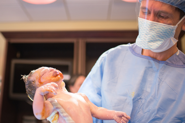 dokter houdt pasgeboren baby vast